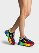 Chunky multicolour trainers angled view showing yellow stripe panels, multicoloured laces and thick rainbow-gradient sole.