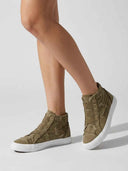 Olive green high-top canvas trainers worn on feet, showing distressed raw-edge upper and chunky white sole, angled view.