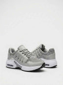 Close-up detail of grey air cushion trainer midsole - visible bubble heel unit, white EVA midsole, and textured black grip outsole.