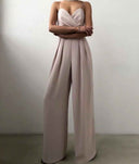 Nude strappy jumpsuit with wide legs and pleated waist, front view.