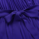 Purple pleated jumpsuit with tied sash, close-up detail.