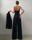 Black spaghetti strap overall with flared hem, back view, holding a jacket.