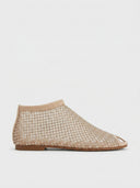 Beige rhinestone-studded fishnet mesh flat slip-on shoes, side view on white background, closed toe silhouette.