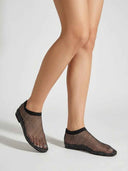 Black rhinestone mesh flat slip-on shoes worn on feet, angled view showing all-over crystal embellishment.