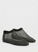 Black rhinestone fishnet flat slip-on shoes on white background, angled view showing closed toe and mesh upper detail.