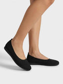 Black knit ballet flat angled view showing ribbed texture, low-cut vamp and heel pull-tab.