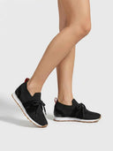 Black knit barefoot trainer with bow laces and white EVA sole, angled three-quarter front view on white background.