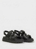 Black lug-sole platform sandals with wide buckle straps, angled three-quarter view on white background.