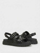 Pair of black buckle platform sandals with chunky tread sole, angled view showing both sandals on white background.
