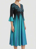 Black and teal gradient V-neck midi dress with bell sleeves and ornate embroidery, angled view.