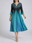 Black and blue gradient midi dress with ornate V-neck, front view on a light gray background.