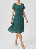 Green mini dress with white polka dots, short sleeves, and gathered waist, front view.