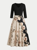 Black V-neck maxi dress with floral print on beige and black skirt, front view.