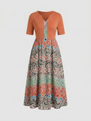 Orange V-neck maxi dress with short sleeves and floral patterned skirt, front view.