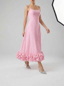 Pink midi dress with spaghetti straps, ruffled hem, and silver heels, angled view.