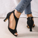 Black peep-toe heeled sandals with cutout T-bar upper, side view styled with blue cropped jeans.