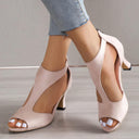 Pink suede-touch peep-toe heeled sandals with cutout T-bar upper and cushioned footbed, angled front view.