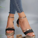 Black block heel sandals with wide glitter toe strap, gold metallic ankle strap and geometric faceted heel — straight front view on neutral background.