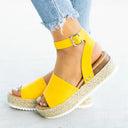 Yellow espadrille flatform sandal with ankle buckle strap and woven jute platform sole, angled side view on foot.