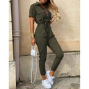 Olive green belted bodycon jumpsuit with decorative buttons, front view against a stone wall.