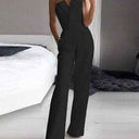 Red sleeveless one-piece jumpsuit with wide legs and V-neck, front view on a bedroom background.