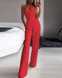 Red strapless jumpsuit with V-neck, pockets, and wide legs, angled view in a bedroom setting.