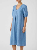 Blue linen midi dress with V-neck, pleated front, and puffed sleeves, angled view.