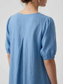 Blue midi dress with puffed sleeves and back pleat detail, rear view.