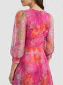 Pink floral mini dress with sheer long sleeves, back view on white background.