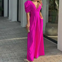 Fuchsia jumpsuit with puff sleeves, V-neck, and wide legs, angled view outdoors.