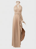 Beige halter-neck maxi dress with tied waist and flowing skirt, front view.