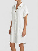 White textured shirt dress with brown buttons, short sleeves, and pockets, angled view.