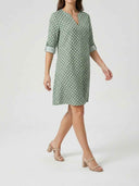Green mini dress with white geometric pattern, split-neck, and rolled 3/4 sleeves, angled view.