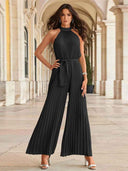 Black pleated halter neck jumpsuit with wide legs and waist tie, front view.