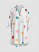 White mini sundress with colorful floral print, button-down front, and rolled sleeves, front view.