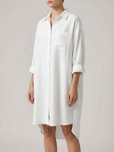 White linen mini sundress with rolled sleeves and front pocket, angled view.