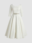 White A-line midi dress with 3/4 sleeves and jeweled belt, front view on gray background.