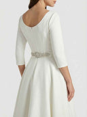 White midi dress, back view, with embellished belt and scoop neck.