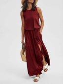 Red sleeveless maxi dress with side slit, straw hat, and bag, angled view.