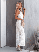 White lace jumpsuit with spaghetti straps, side view against a gray wall.