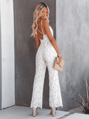 White lace jumpsuit with criss-cross back straps, angled back view.