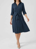 Navy blue button-down shirt dress with tied waist, rolled sleeves, front view.