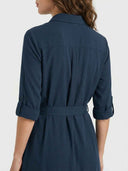 Navy mini dress with rolled sleeves, belted waist, and back pleats, rear view.