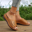 Brown low wedge slip-on sandal showing cushioned sole, contrast white topstitching, and perforated upper, angled side view.