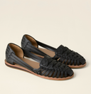 Black closed-toe woven flat sandals with huarache strap upper and slim ankle strap, angled three-quarter view on a neutral background.