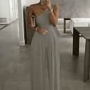 Gray asymmetrical one-shoulder jumpsuit with wide pleated legs, worn by a model, front view.