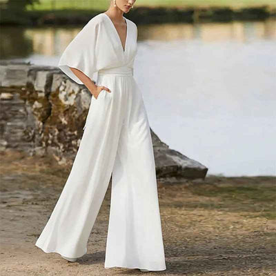 White dolman sleeve jumpsuit with V-neck, cinched waist, and wide legs, angled view outdoors.