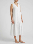 White sleeveless V-neck dress with front buttons and ruffled hem, angled front view.