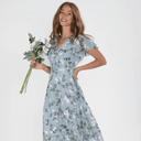 Woman in light blue botanical print maxi dress with flutter sleeves, front view.