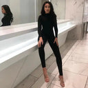 Black long-sleeve slim-fit jumpsuit with mock neck, angled view on a tiled floor.